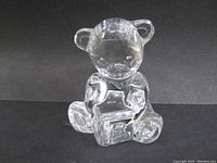 Front view of clear lead crystal teddy bear paperweight sitting upright holding a block with detailed facial features and rounded ears.