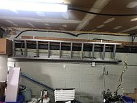 Full view of the aluminum extension ladder mounted on a garage wall, showing the length and structure.