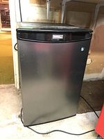 Front view of Danby Designer compact bar refrigerator showing stainless steel door with black trim and Danby logo.