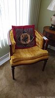 Front angle view of wood chair with mustard yellow tufted upholstered seat and a red decorative pillow.