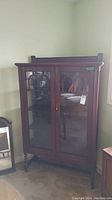 Front view of vintage oak china cabinet showing two glass doors with wood framing and decorative arches at the top.