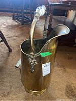 Brass coal scuttle displaying front and side views, showing porcelain handle grips and curved spout design.