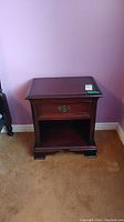 Front view of mahogany nightstand showing drawer, open shelf, and bracket feet