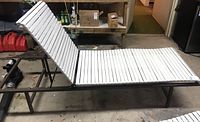 Full side view of white slatted lounger with coated metal frame in garage surroundings.