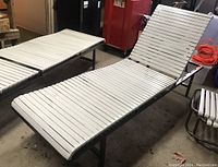 View of the lounger angled to show the adjustable backrest with white slats on a coated steel frame in a garage setting.