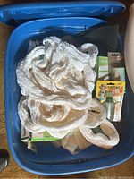 Blue plastic bin with white thick cotton rope piled on top, box of syringes and other supplies underneath