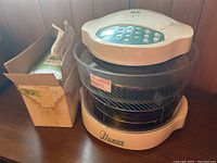 NuWave infrared oven with digital control panel and accessories, alongside original boxed mandolin slicer