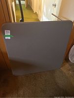 Top view of square metal folding table's vinyl surface showing some minor scratches.