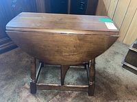 Photo of the folded drop leaf wooden side table showing the compact profile and wooden finish.