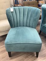 Front view of teal velour accent chair showing vertical channel tufted backrest and wooden legs.