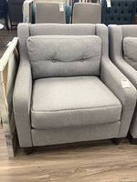 Front view of light grey fabric armchair showing seat cushion and button-tufted back cushion