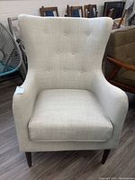 Front view of beige fabric armchair showing button tufted back and removable cushion