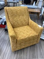 Front view of mustard yellow fabric armchair showing angled armrests and cushioned seat and backrest.