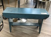 Side view of a blue painted wooden bench showing overall structure and height.