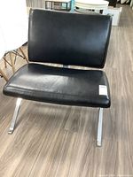 Front angle showing entire black faux leather chair with wide seat and backrest, chrome legs visible.