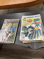 Bagged Strange Tales comic alongside a stack of additional comics on tabletop