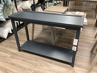 Full view of dark gray painted wood console table showing rectangular top, lower shelf, and legs.