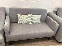 Front view of grey loveseat with two throw cushions