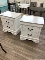 Front view of both white nightstands side by side on wood floor