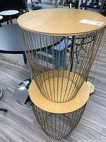 Pair of round wood top side tables with metal cage bases stacked on each other.