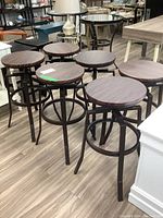 Six metal bar stools with round woodgrain seats arranged on showroom floor