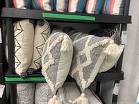 Full view of multiple throw cushions on shelf featuring different patterns and tassels
