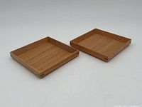 Two handmade wooden trays positioned side by side, showing square shape and dovetail corner details.