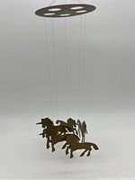 Full view of the brass mobile showing unicorn figures hanging from a circular frame.