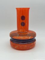 Front view of the orange vase with purple dots and ring, showing vase shape and pattern.