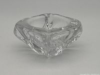 Angled top view showing the clear glass bowl's organic triangular shape with thick glass and smooth polished finish.