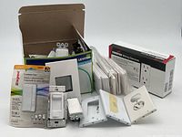 Lot showing packaged Legrand countdown timer, Leviton dimmer, multiple switches, and outlet covers with some outlet boxes.