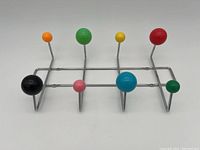 Full view of chrome wireframe wall-mounted hanger with eight multicolored ball hooks.