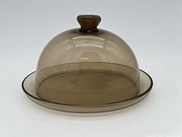 Side view of MCM lidded glass dish showing dome lid and round base plate with knob handle on lid.