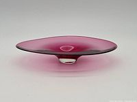 Side angled view of the pink Jan Benda glass dish showing its elegant curved shape and base.