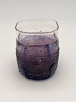 Square purple textured art glass cup showing front side with visible ripples, bubbles, and clear upper rim.