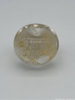 Clear glass apple-shaped paperweight with internal textured gold and white pattern, smooth polished surface, photographed from multiple angles to show form and detail.