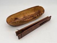 Photo showing olive wood tray and walnut tongs side by side, highlighting shape, wood grain, and size.