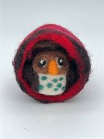 Front view of wool felt brown owl inside the red and black wool nest