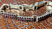 Close-up of sterling silver two-row garnet tennis bracelet showing rows of small garnets and clasp.