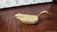 Front angled view of gilded swan trinket box showing detailed feather texture and curved neck