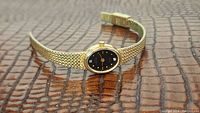 Full view of ladies Jules Jurgensen watch with black diamond dial and gold mesh bracelet.