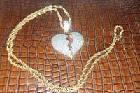 Full view of gold-tone rope chain and broken heart pendant laid flat