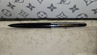 Full length view of the black and silver Waterman pen with red push button.