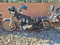 Side view of the 1980 Honda CB750K motorcycle salvage showing the frame, engine, front and rear wheels, handlebars with mirrors, rear luggage rack and backrest.