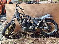 Side view of Yamaha motorcycle salvage showing frame, engine block, front wheel and some components on dirt ground