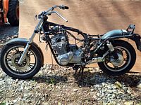 Side view of vintage 1982 Suzuki GS1100GK motorcycle frame showing engine, front and rear wheels, chrome handlebars, and wiring harness.