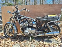 Left side view of the 1982 Suzuki GS750T motorcycle salvage showing engine, frame, front and rear suspension, seat with damaged upholstery, handlebars and chrome front fender.