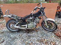 Wide side view showing the motorcycle frame, engine, rear and front wheels, and exhaust system.