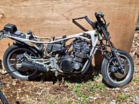 Side view of a stripped 1983 Suzuki GS550ESD motorcycle frame showing engine, rear wheel, swingarm, and partial rear frame structure