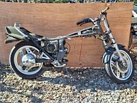 Side view of salvaged 1984 Honda CX650E motorcycle frame showing engine block, front and rear wheels, and partial bodywork in outdoor setting.